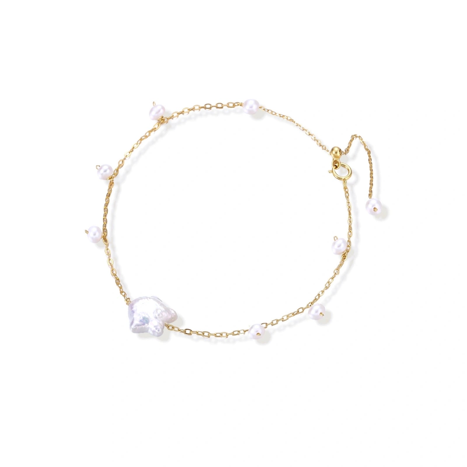 Delicate gold chain bracelet with baroque pearl centerpiece and small freshwater pearls on cream background.
