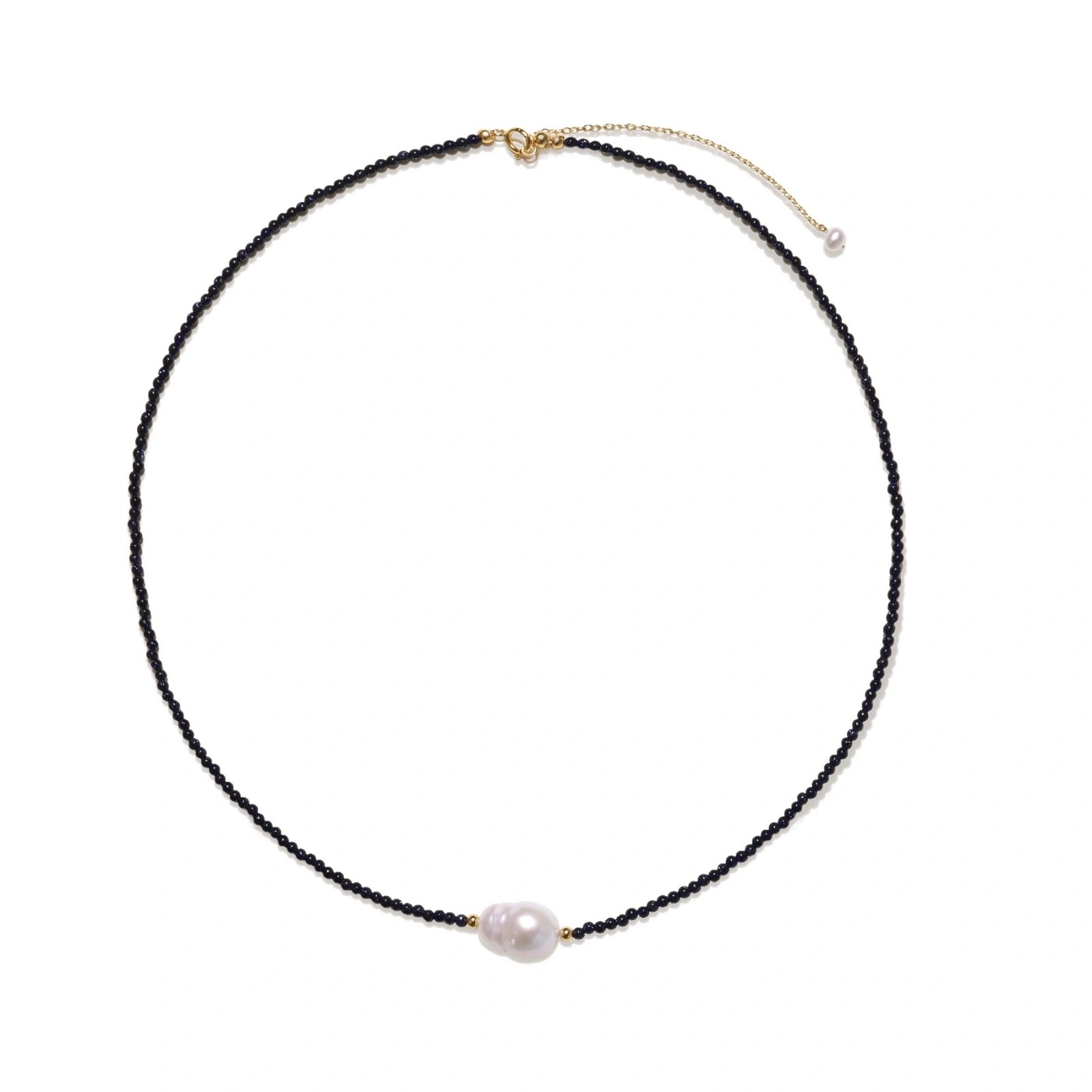 Delicate necklace with black blue sandstone beads and baroque pearl center on white background with gold accents.