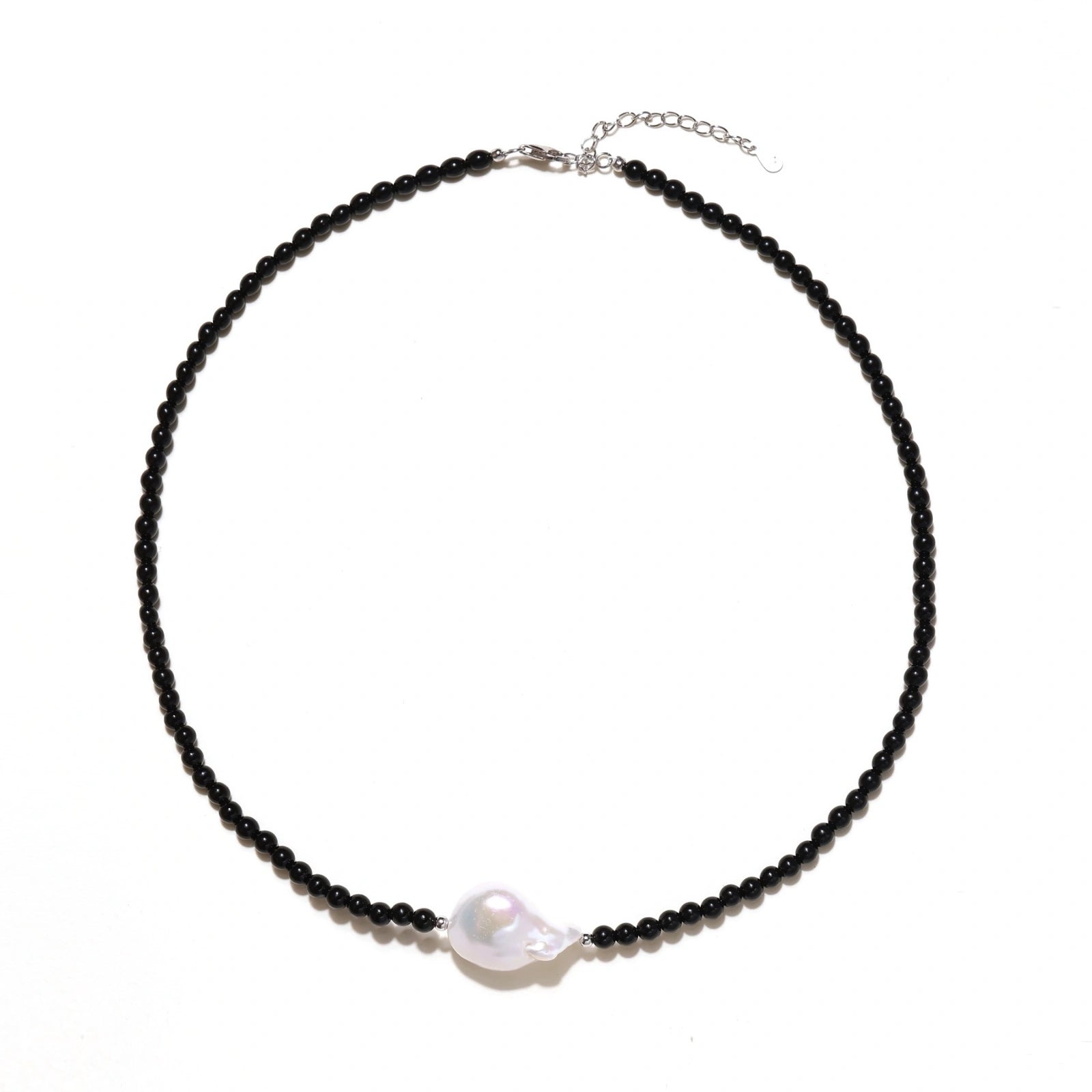 Beaded black agate necklace with iridescent baroque freshwater pearl centerpiece on cream background.