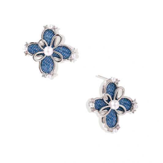 Blue denim fabric flower studs with white gold plated petals, pearl center, and zirconia accents on white background