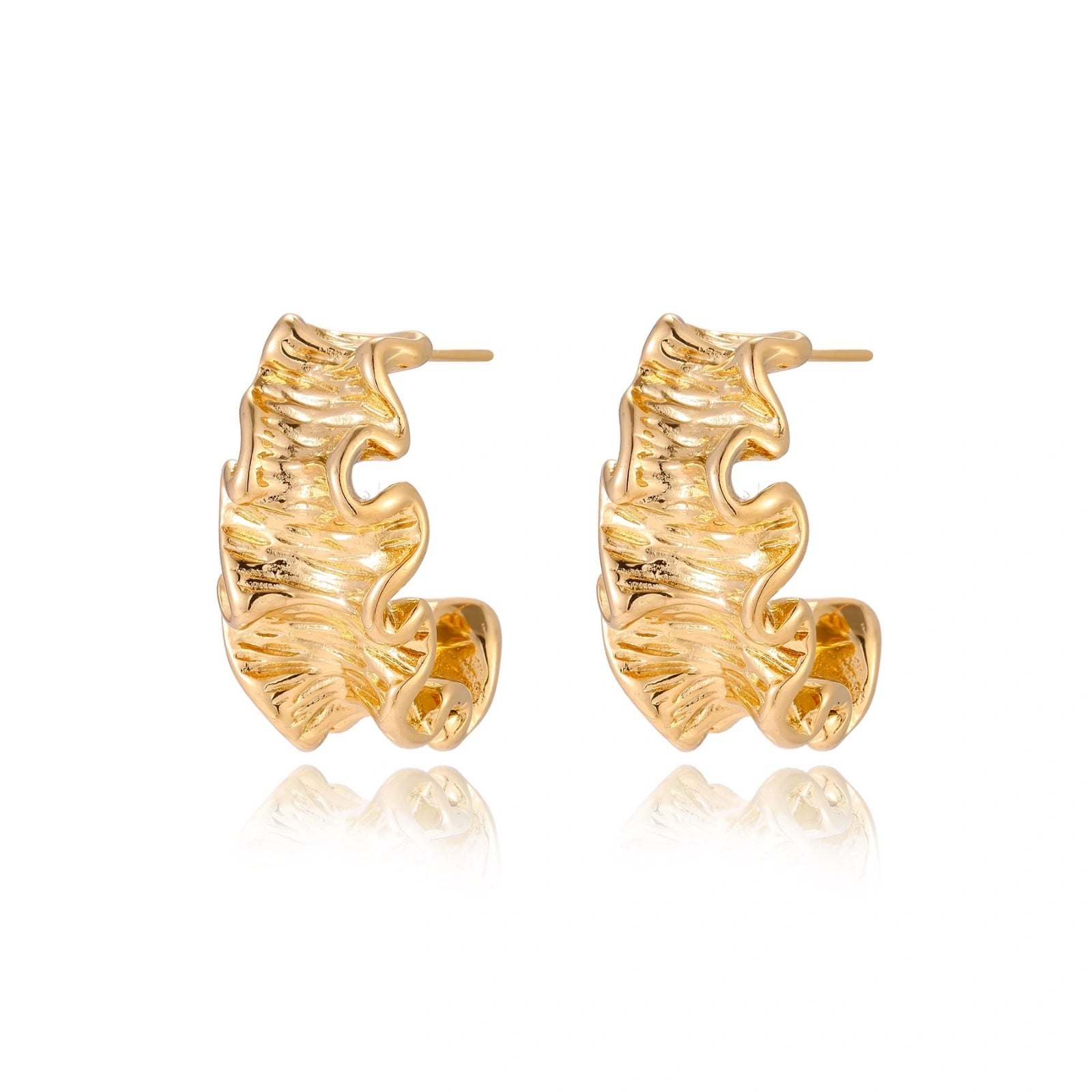 Pair of gold huggie hoops with sculpted wave texture and dimensional ripples on neutral background.