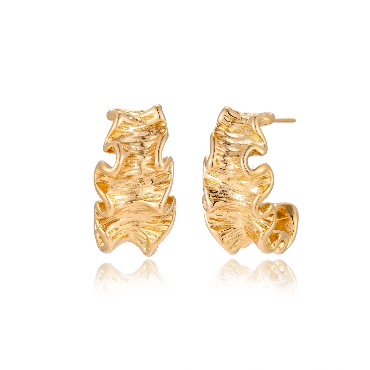 Pair of gold huggie hoops with sculpted wave texture and dimensional ripples on neutral background.
